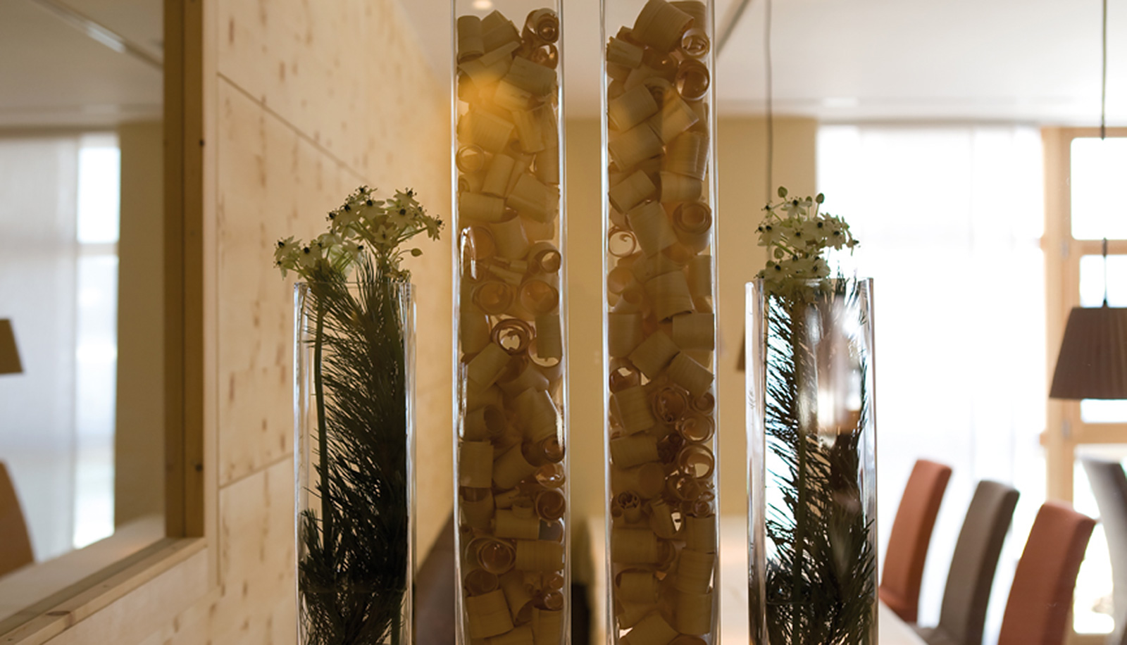 Decoration with woodchips and flowers in tall glass vases