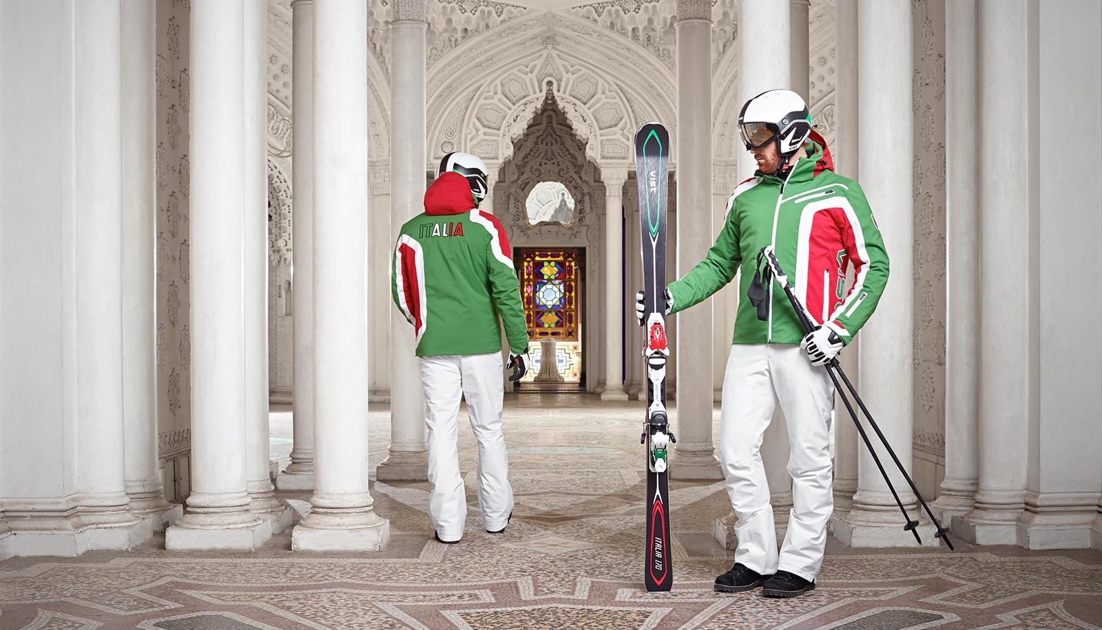 Zwei Skifahrer mit kompletter Ausrüstung in einer orientalisch anmutenden Halle