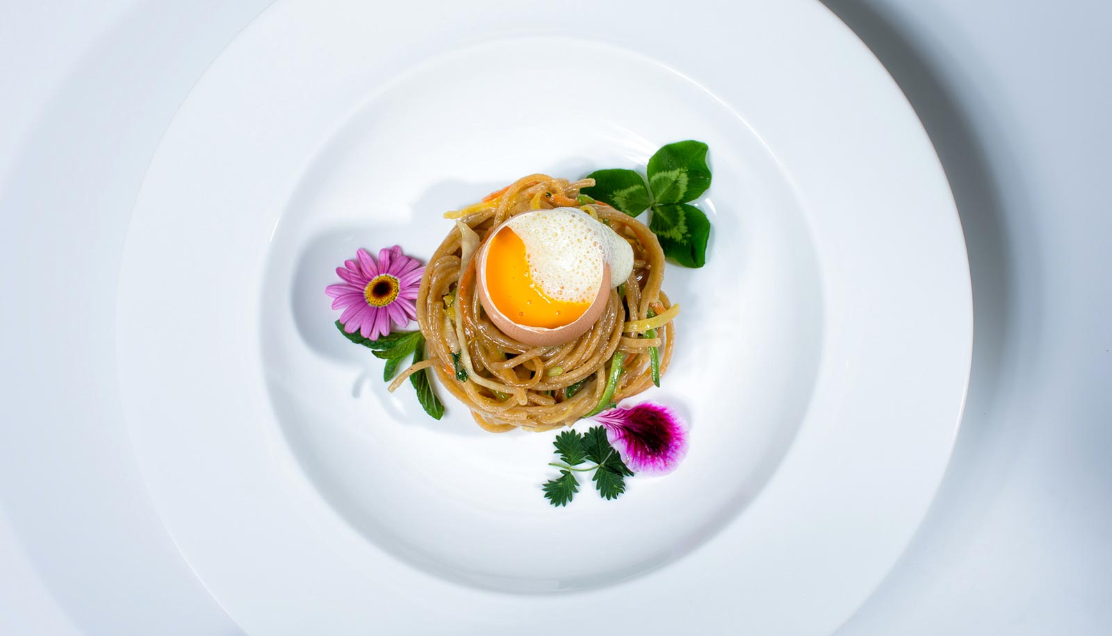 Spaghetti mit Gemüse und ganzem Ei, mit Blumen dekoriert