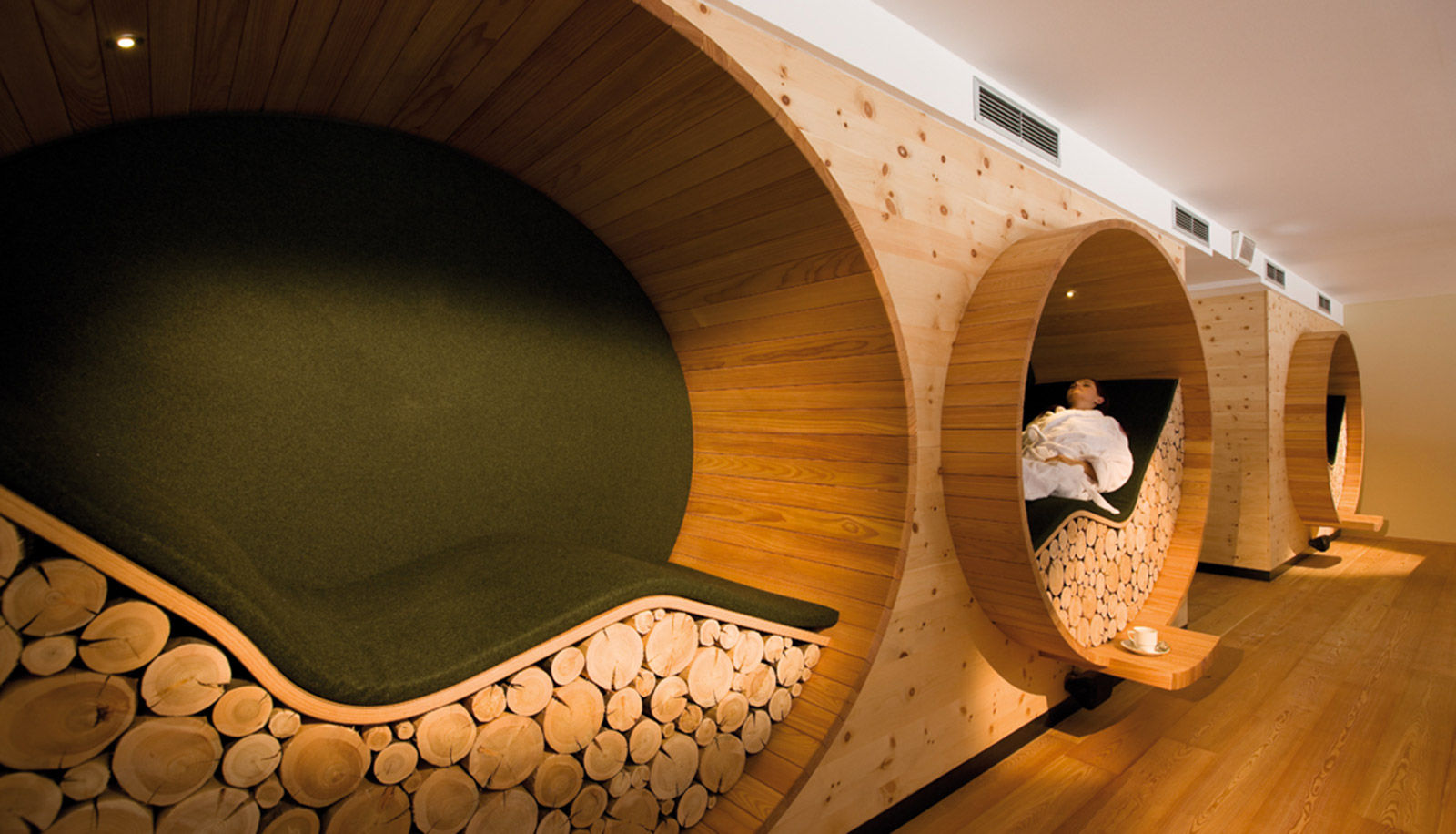 Two wooden lounge bed made of logs at Arosea Hotel in Ultental-Val d'Ultimo, on which a woman is resting