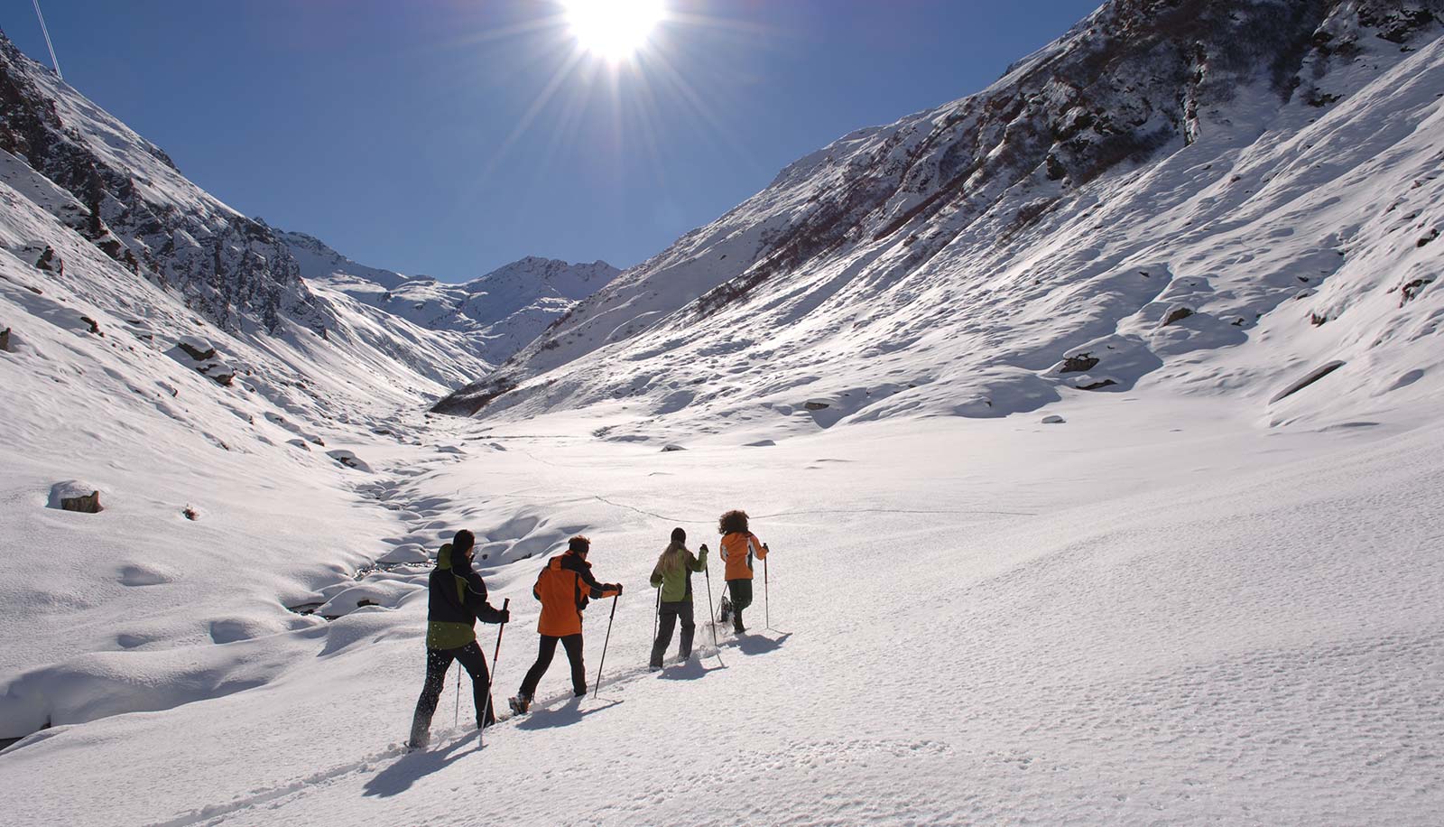 Quattro ciaspolatori nella neve in una giornata di sole