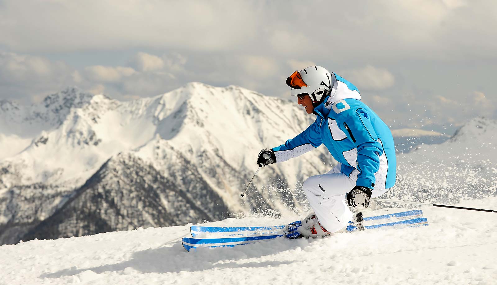 Ein Skifahrer auf der Piste mit verschneiten Bergen im Hintergrund