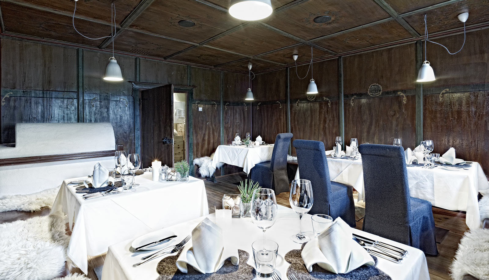 Stube mit dunkler Holzverkleidung, Ofen und gedeckten Tischen im im Arosea Life Balance Hotel im Ultental
