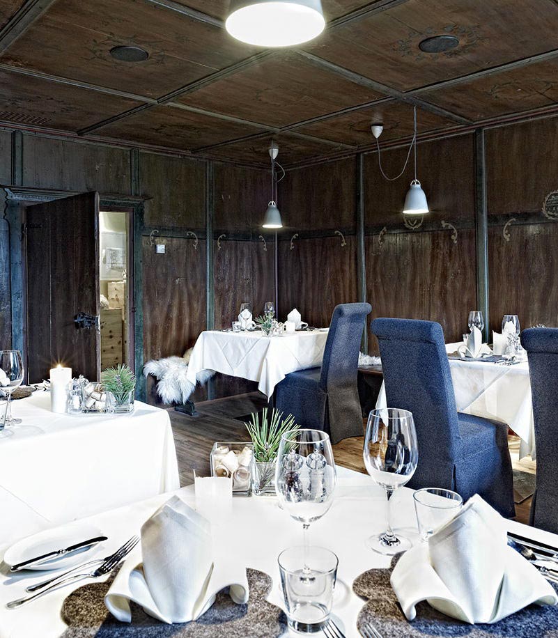 Tavoli imbanditi in una stube con legno scuro dell'Arosea Life Balance Hotel in Val d'Ultimo