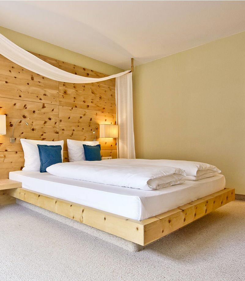 Doppelbett mit Holzwand in einem Zimmer des Arosea Life Balance Hotels im Ultental